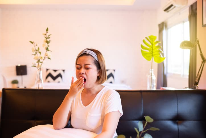 Asian woman yawning during sitting on sofa and tired sleepy,Female with symptoms sleepiness