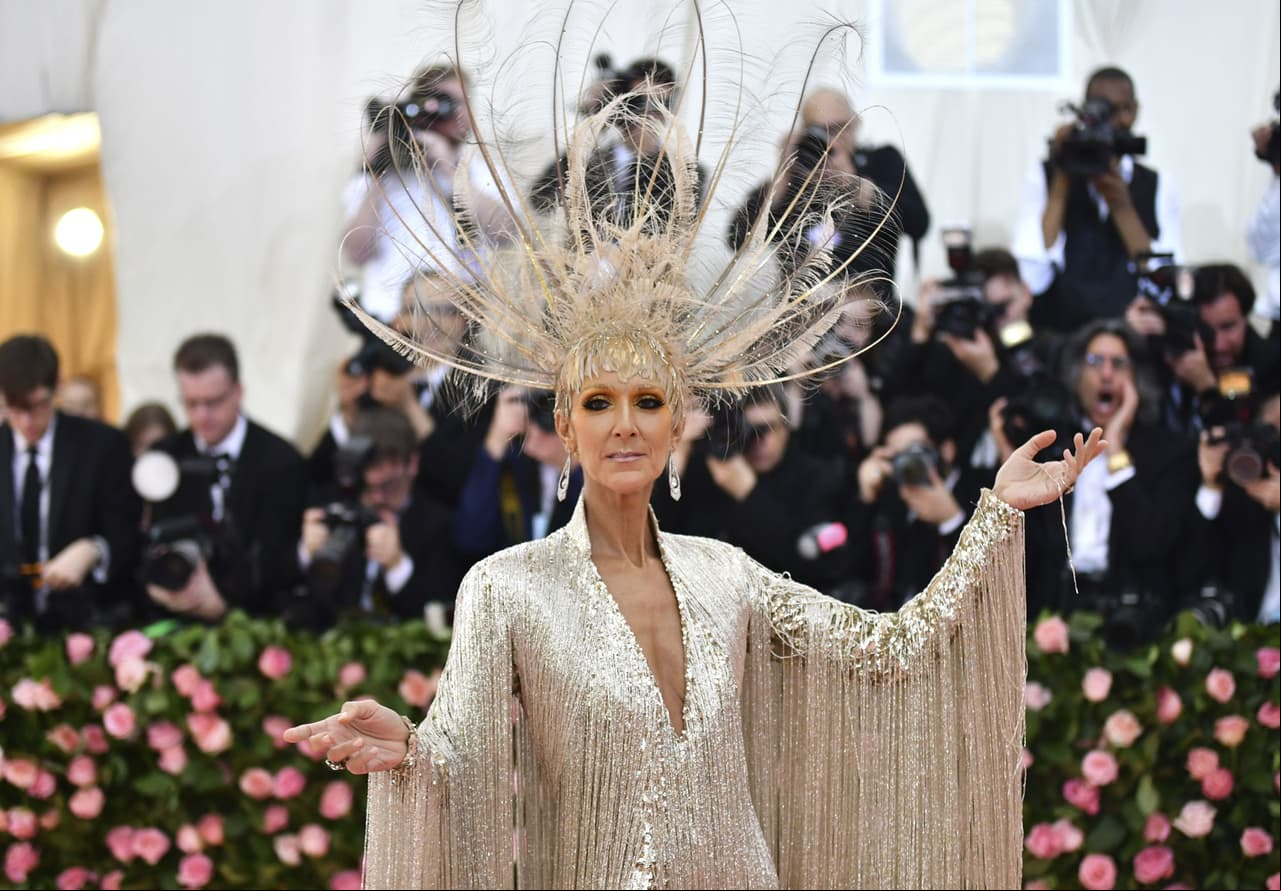 La cantante Céline Dion optó por un atuendo atrevido e impactó en la alfombra con un traje de flecos plateado con un casco de plumas de Oscar de la Renta.