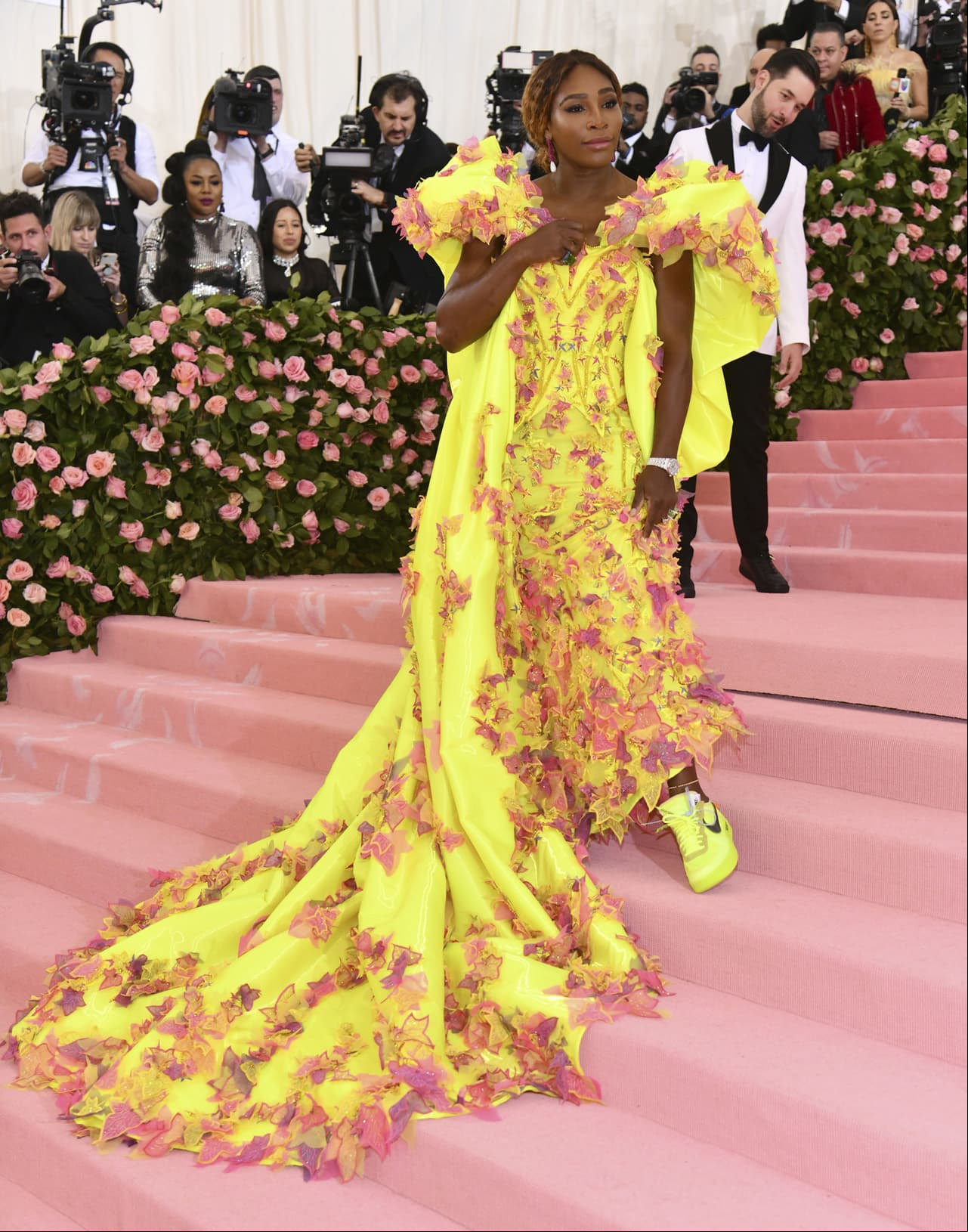 Serena Williams, quien será una de las presentadoras del evento junto a Lady Gaga y Harry Styles, camina por la alfombra rosa con un vestido amarillo neón de Versace.