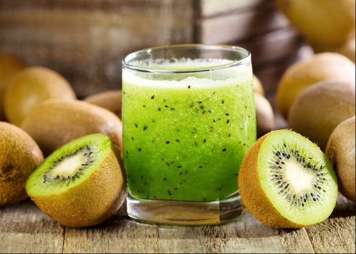glass of kiwi juice with fresh fruits on wooden table