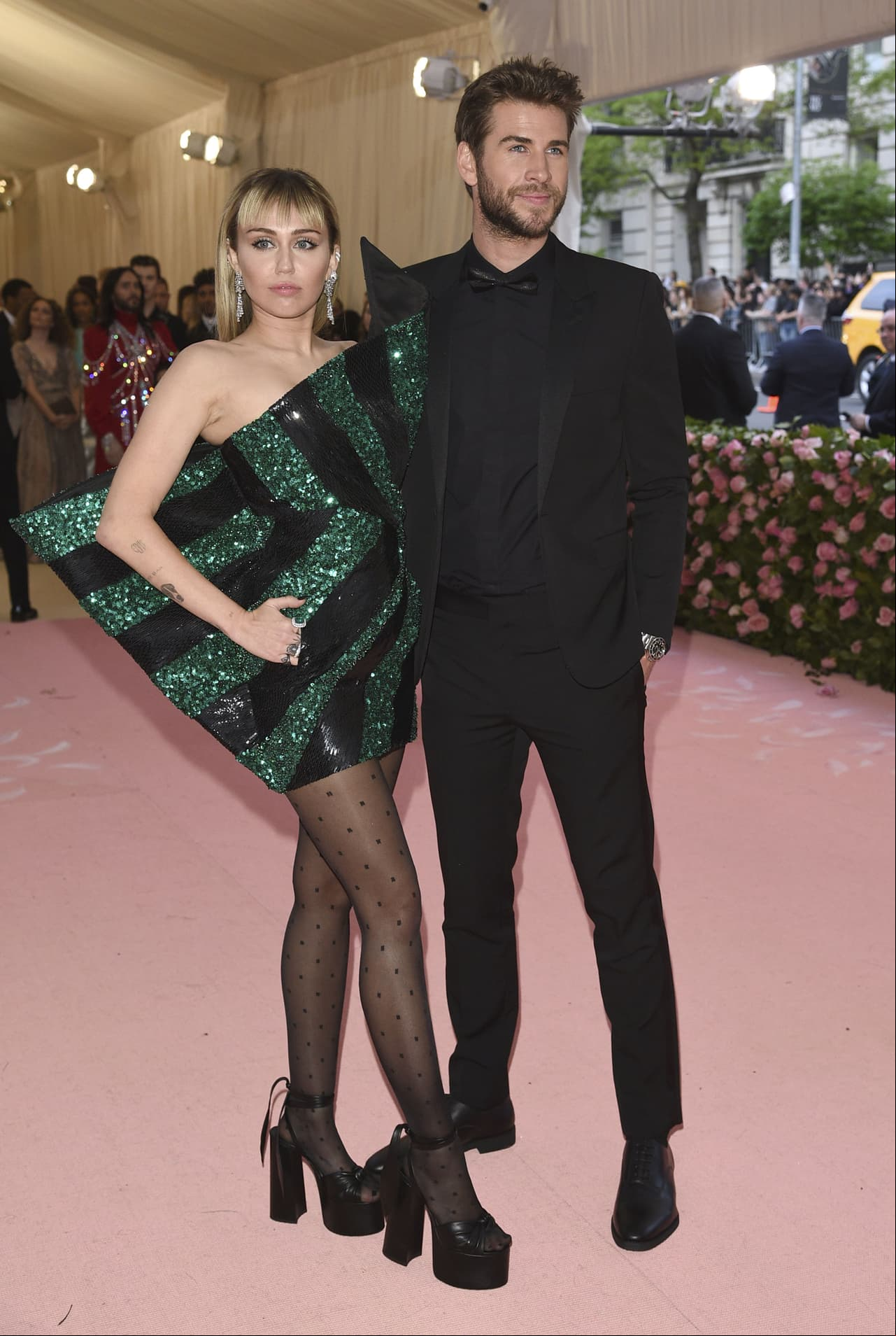 Miley Cyrus, acompañada de su esposo Liam Hemsworth, eligió un diseño en esmeralda y lentejuelas negras de Saint Laurent.