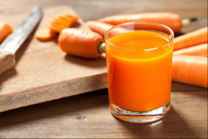 Close up of carrot juice on old wood floor. This file is cleaned and retouched.